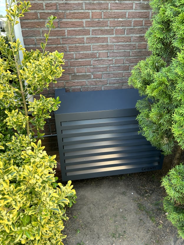 Moderne buitenventilatiekast naast tuinplanten